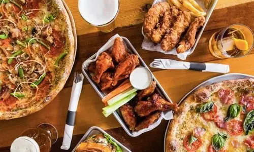 A table at Standard spread with pizzas, wings, tenders and cold drinks